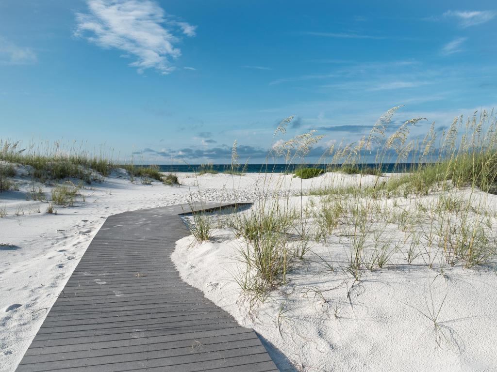 Destin, Florida, USA taken at a small rustic boardwalk footpath through snow white sand dunes at a pristine Florida beach.