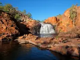Red stone cliff with small waterfall into pool