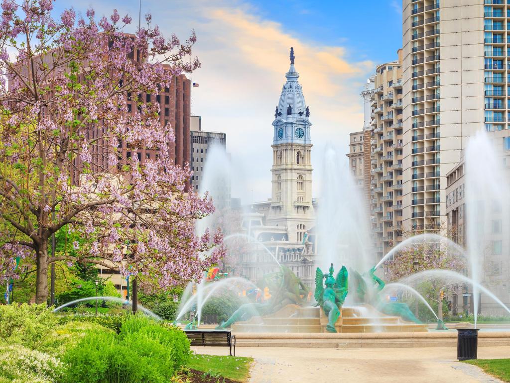 Philadelphia, Pennsylvania, USA taken at the Swann Memorial Fountain with the City Hall in the background, pink blossom and a blue sky.
