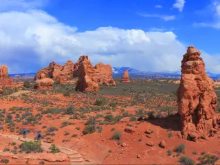 Arches National Park, Utah, USA taken on a sunny day with the red stone formations and a path leading through them with walkers. 
