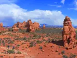 Arches National Park, Utah, USA taken on a sunny day with the red stone formations and a path leading through them with walkers. 