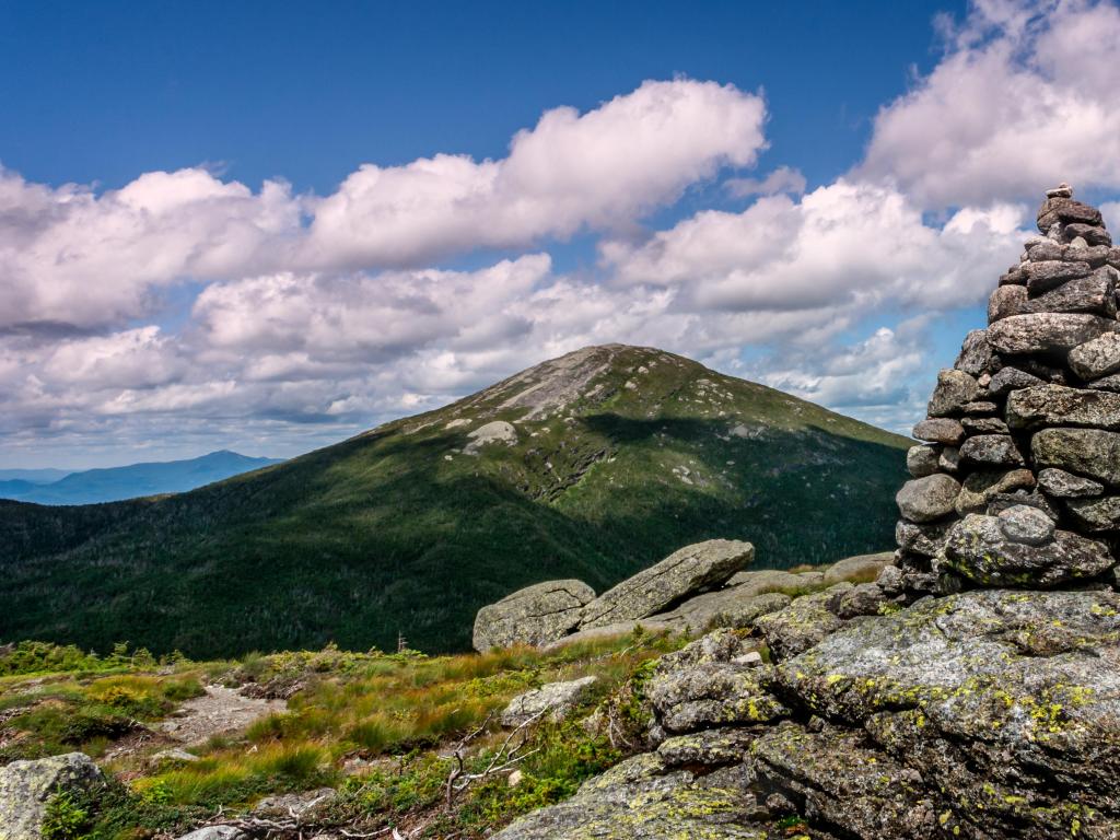 Mt. Marcy, USA with a rock tower in the foreground and looking to the mountain in the distance on a sunny and cloudy day. 