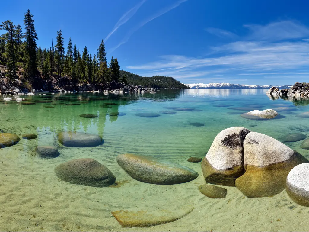 Lake Tahoe, Nevada, USA with a beautiful panorama on the beach of Secret Cove, taken on a sunny day with clear turquoise water and trees in the distance. 
