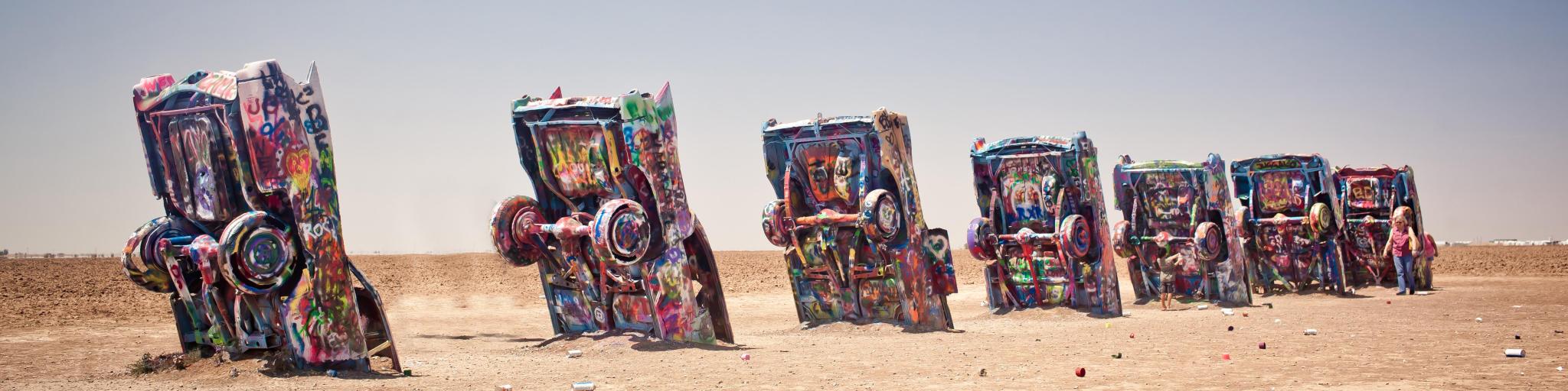 Graffiti-covered Cadillac cars in an art installation, sticking out of the ground in the desert