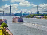 Savannah waterfront with ship sailing in the water, bridge in the background