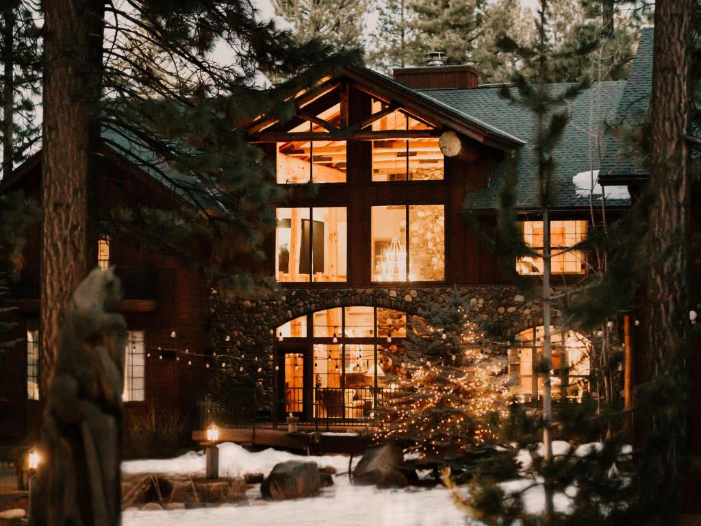 Exterior of Black Bear Lodge, Lake Tahoe, with light filled entrance of lodge, surrounded by woodland 