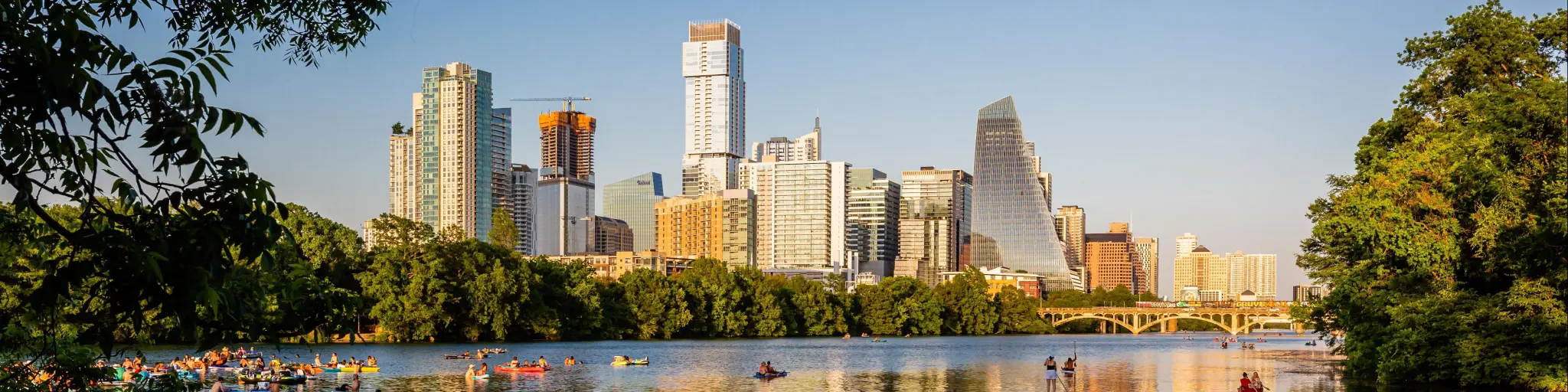 Austin skyline on a clear day and its reflection on Lady Bird Lake, dotted with boaters
