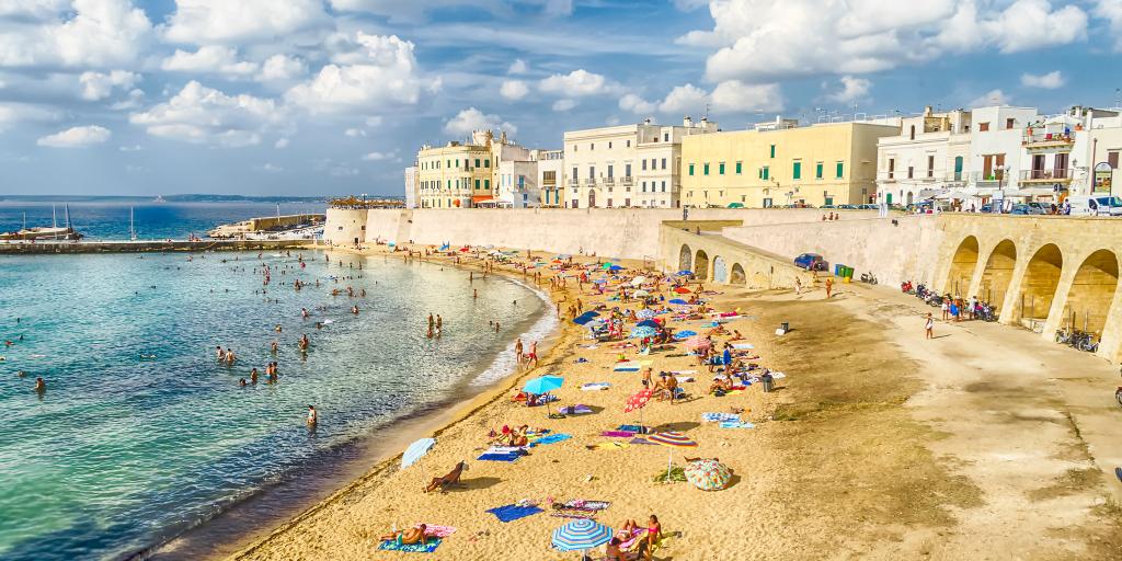 People relaxing on Purity Beach with the town walls behind in Galipolli, Puglia 