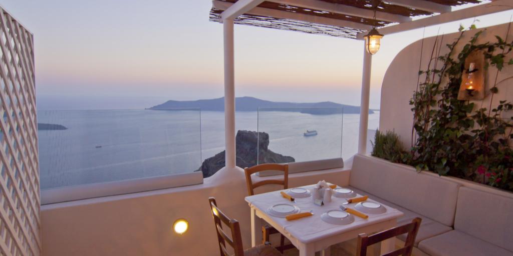 A table set for four with views of the caldera in Santorini at dusk