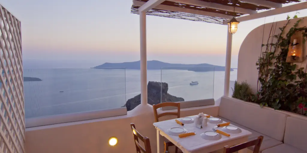 A table set for four with views of the caldera in Santorini at dusk