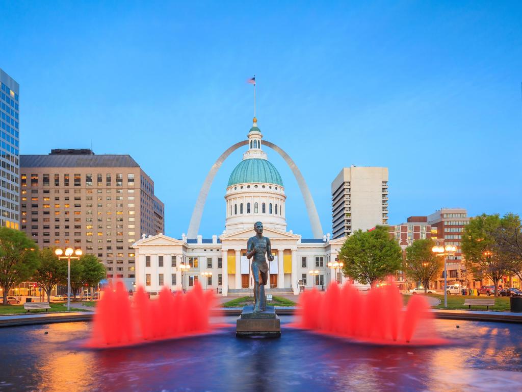 St Louis Old Courthouse with statue and red lit up fountains outside at twilight