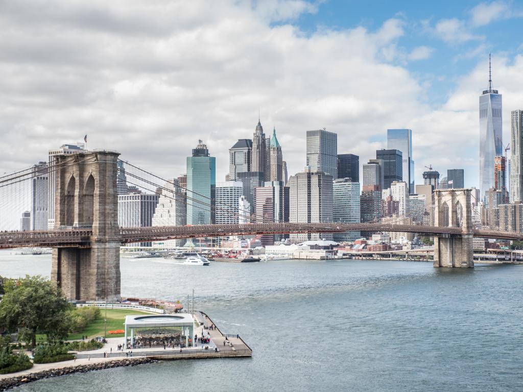 New York City, USA with a view of Brooklyn Bridge and Manhattan skyline taken from Manhattan Bridge on a sunny and cloudy day.