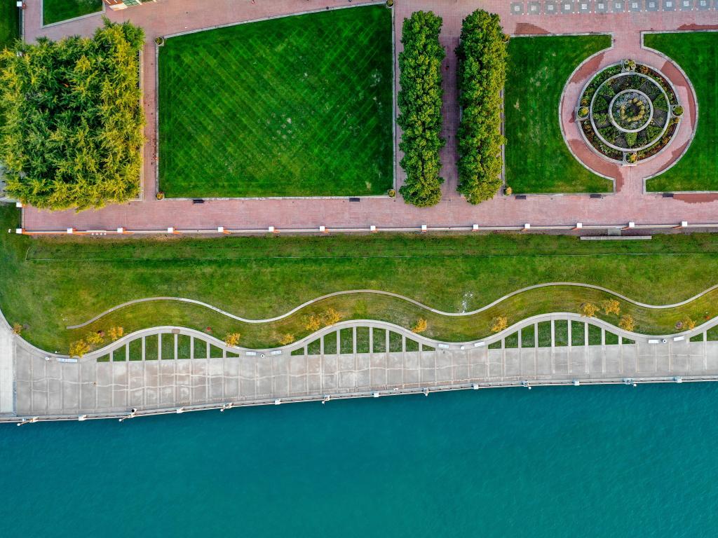 Ariel view of Detroit Riverwalk with green manicured gardens, and winding pathways along the waterfront