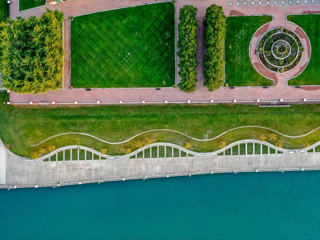 Ariel view of Detroit Riverwalk with green manicured gardens, and winding pathways along the waterfront