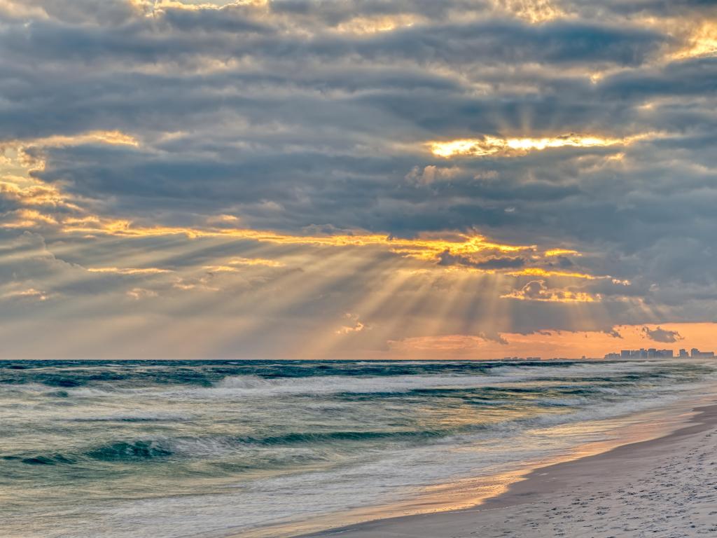 Santa Rosa Beach, Florida, USA with dramatic pastel light sunset with sun rays at Pensacola coastline coast cityscape skyline in panhandle and ocean.