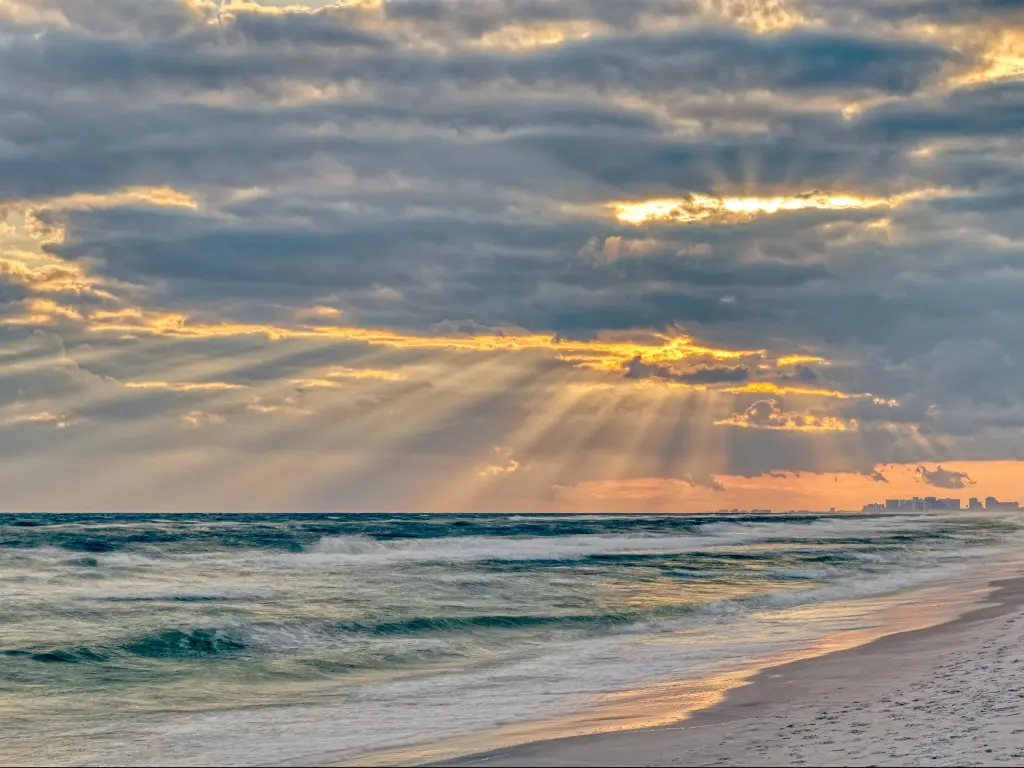 Santa Rosa Beach, Florida, USA with dramatic pastel light sunset with sun rays at Pensacola coastline coast cityscape skyline in panhandle and ocean.