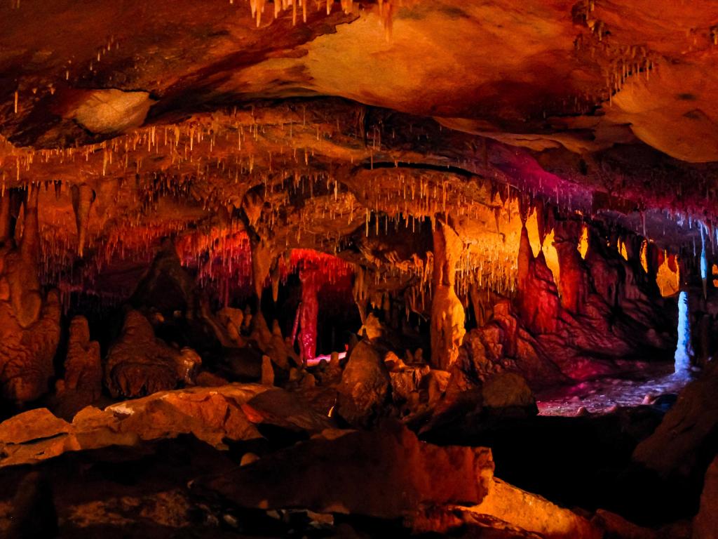 Inner Space Caverns, Georgetown a dark cave illuminated with reds, oranges and yellows.