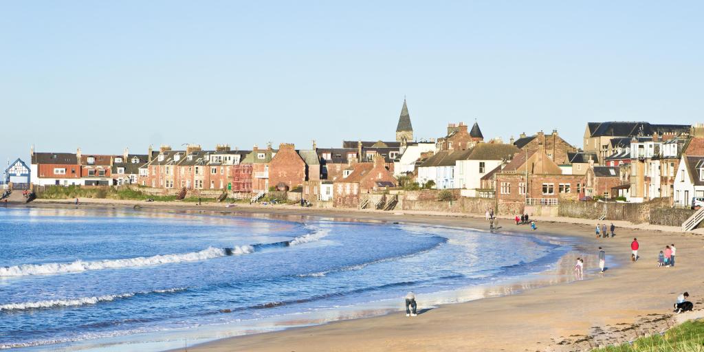 People walk along the beach on a sunny day in North Berwick, Scotland