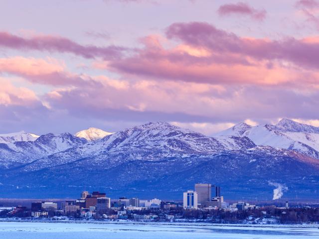 Anchorage, Alaska, USA with the city skyline in winter at dusk with the Chugach mountains behind.