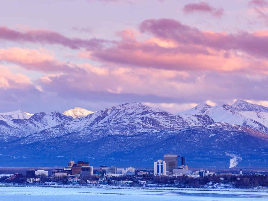 Anchorage, Alaska, USA with the city skyline in winter at dusk with the Chugach mountains behind.