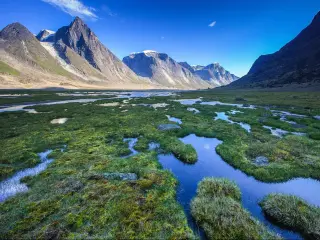 Panoramic view of the rugged Akshayuk Pass, Nunavut, Canada, with a blue sky above