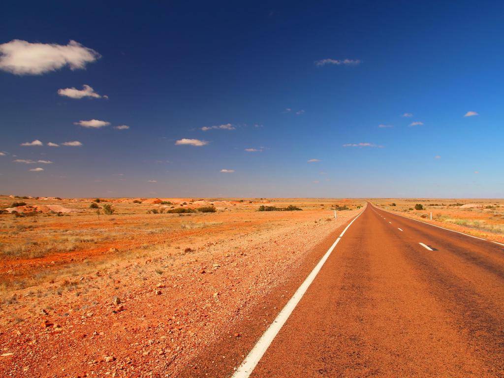 Stuart Highway, Australia a view of the Australian highway through the outback showing orange desert on a sunny clear day.