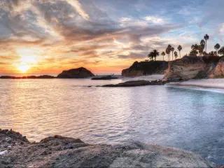 Rocks and sandy beach with sandy cliffs and palm trees