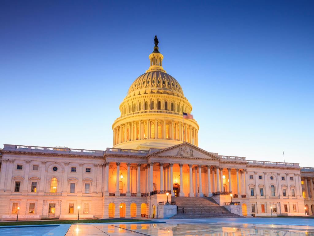 Washington DC, USA with a view of the United States Capitol building with the dome lit up at night.