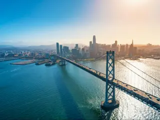 Bay Bridge in San Francisco, CA, USA taken as an aerial view with the city skyline in the distance and taken just as the sun is beginning to set on a clear day.