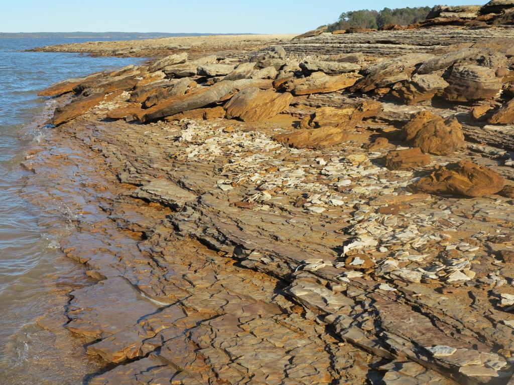 Rugged clay stone beach with clear waters on a bright day