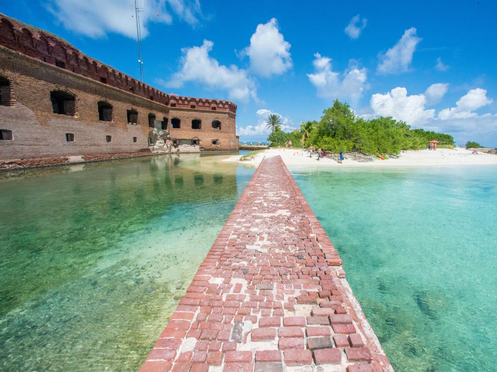 Dry Tortugas National Park, Fort Jefferson. Florida Keys with a bridge made from bricks leading to a moat and an old building, surrounded by beautiful clear water on a sunny day.