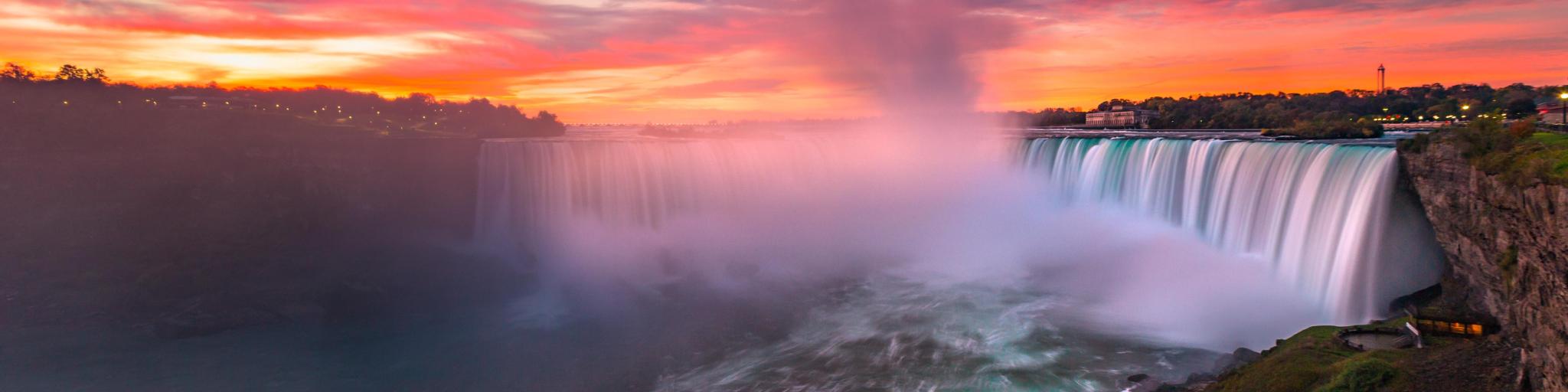Niagara Falls, USA/Canada with the stunning falls taken at dawn with a sky of red, yellows and orange and spray around the river.