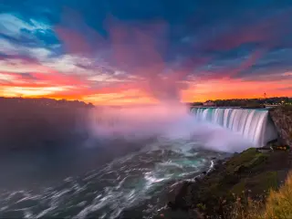 Niagara Falls, USA/Canada with the stunning falls taken at dawn with a sky of red, yellows and orange and spray around the river.
