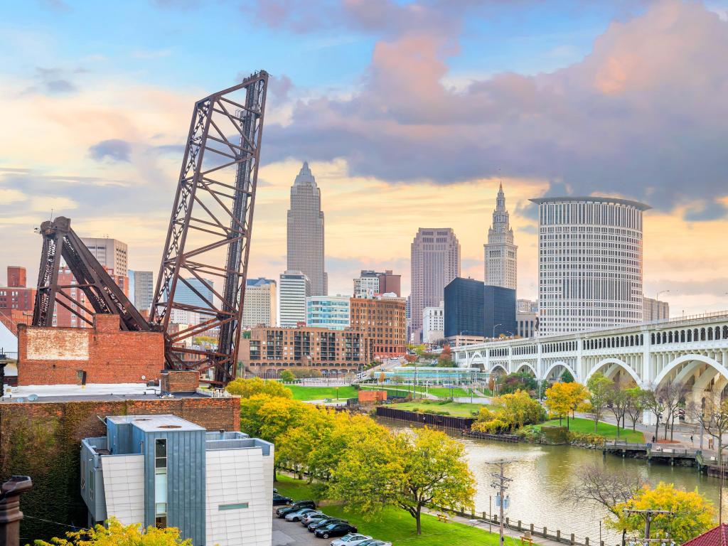 Cleveland, Ohio, USA with a view of the downtown skyline at sunset with the river and trees in the foreground. 