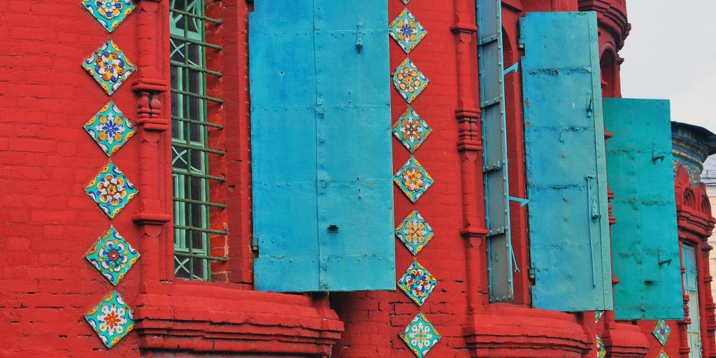 A close up of three decorative blue window shutters against red brickwork at the Church of the Epiphany, Yaroslavl, Russia