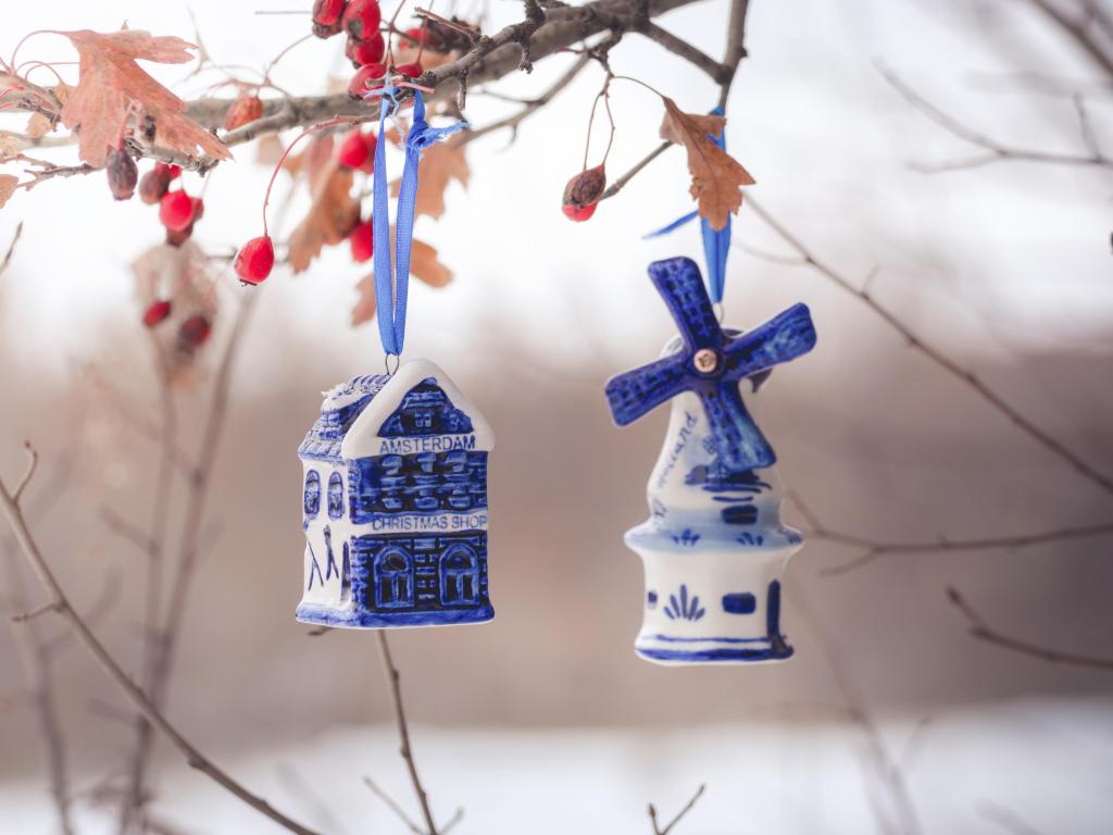 Blue ceramic Christmas toy bought in Amsterdam hangs on a branch