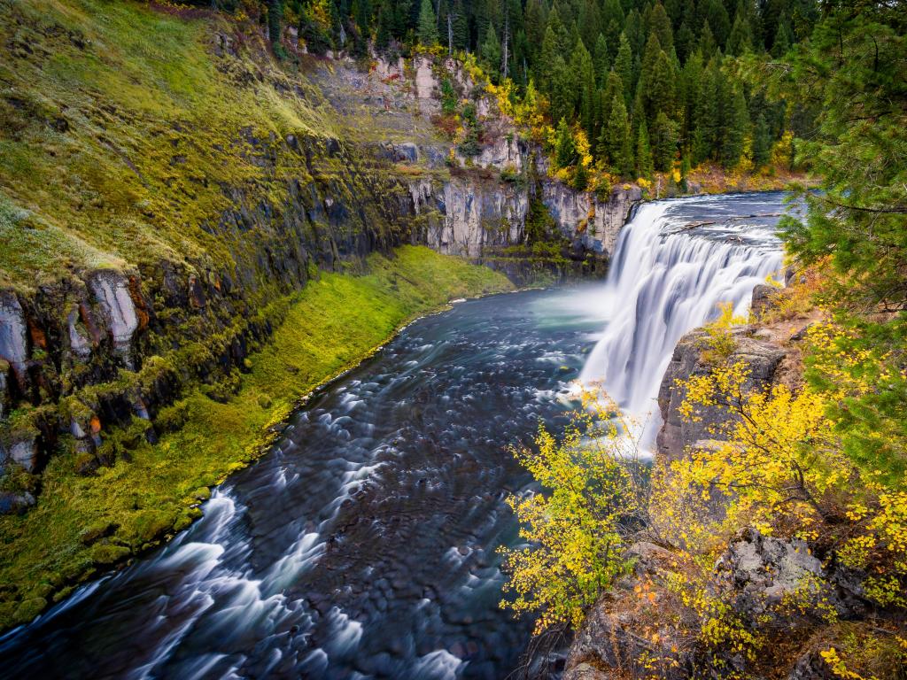 Autumn at the Upper Mesa Falls, Idaho, USA with a huge waterfall surrounded by dense forest.