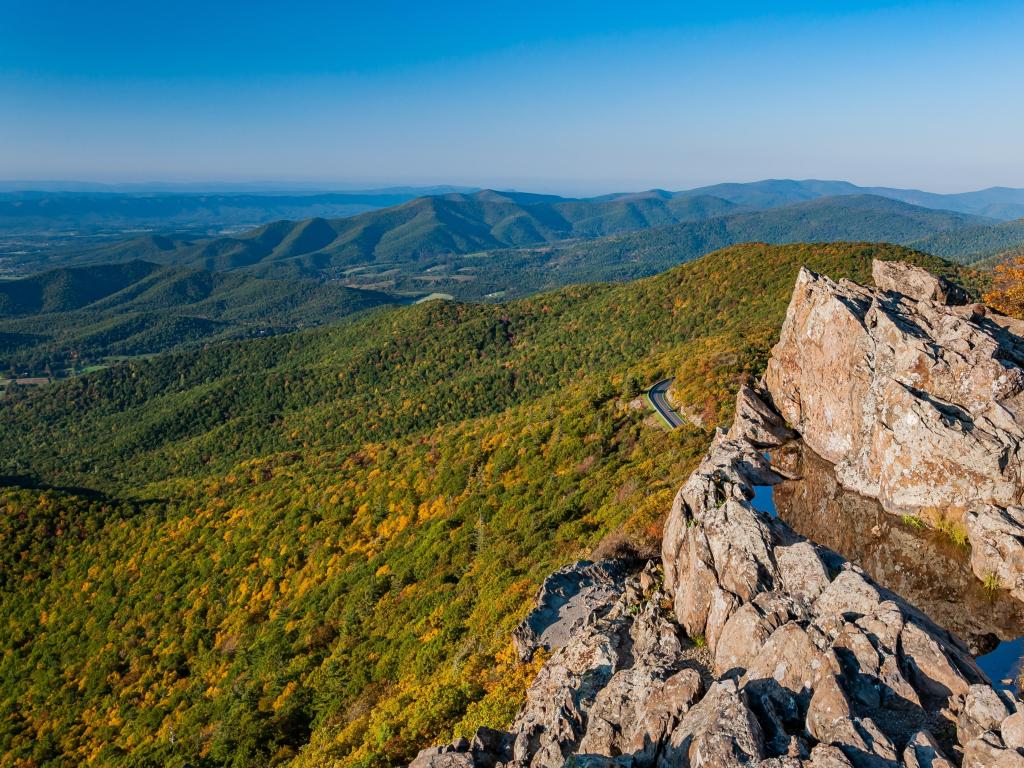 View from the Stony Man Cliffs to the autumnal foliage of the trees below, blue skies