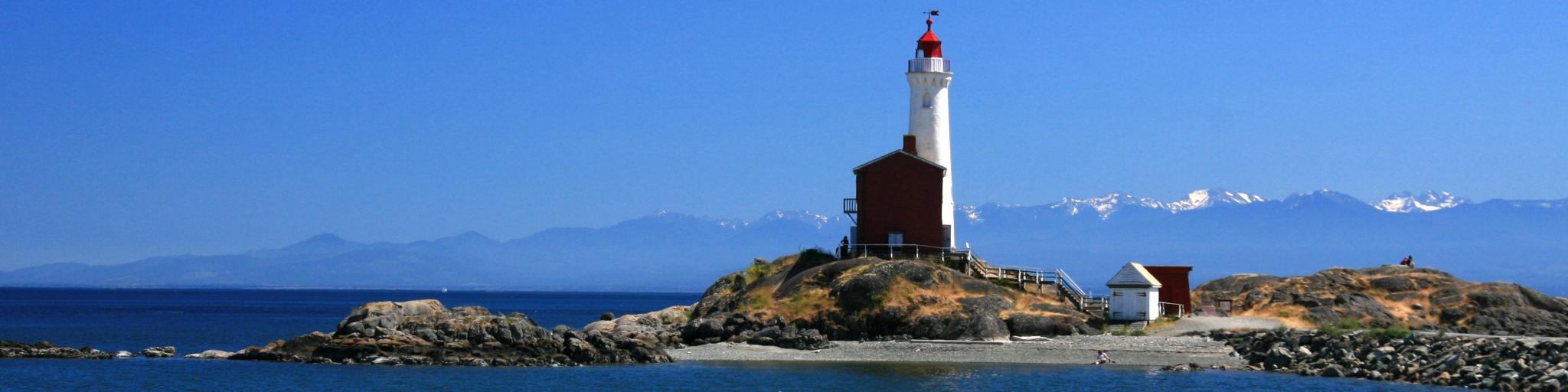Beautiful lighthouse on a sunny day with mountains in the background in Victoria, Vancouver Island