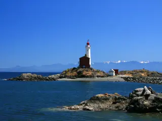 Beautiful lighthouse on a sunny day with mountains in the background in Victoria, Vancouver Island