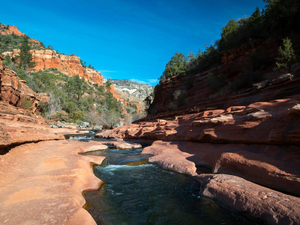 Calm river flowing between rocky shores in an orange rocky valley