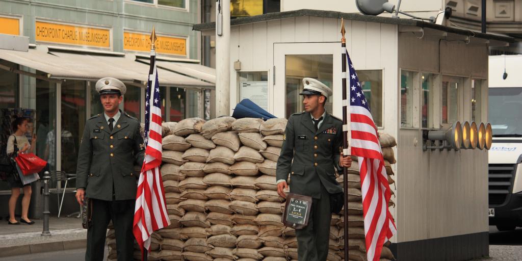 Two guards hold American flags at Checkpoint Charlie in Berlin