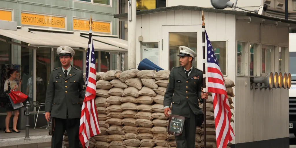 Two guards hold American flags at Checkpoint Charlie in Berlin