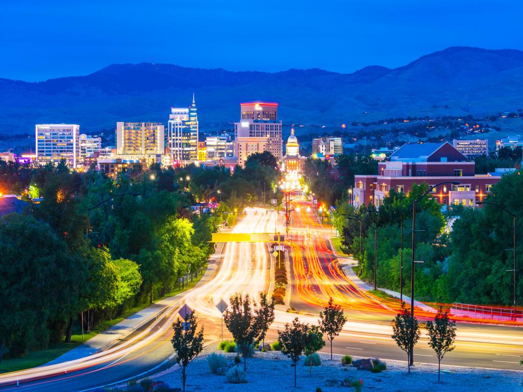 Boise, Idaho, USA with the cityscape taken at night with traffic lights and street lights and the mountains in the distance. 