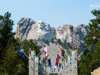 Entrance to Mount Rushmore surrounded with US flags and Mount Rushmore in the background, South Dakota
