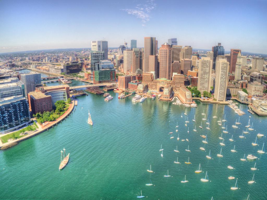 High rise buildings along the city waterfront with blue sky and turquoise water with small  boats