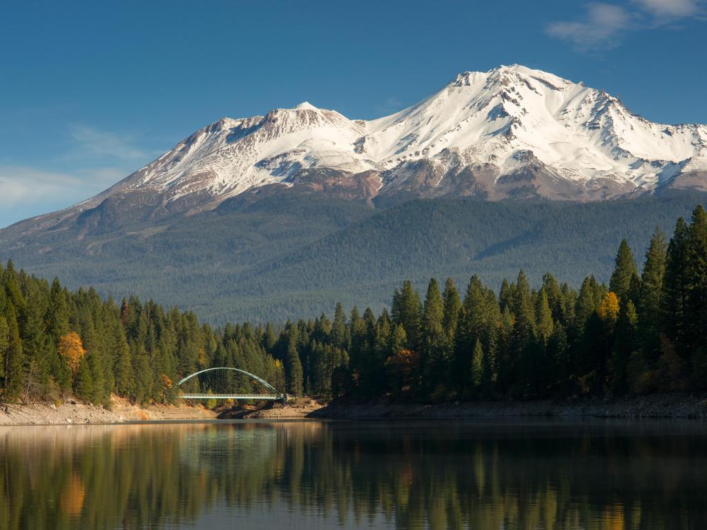 Mount Shasta  standing above Lake Siskiyou with suspension bridge in the background on a sunny day