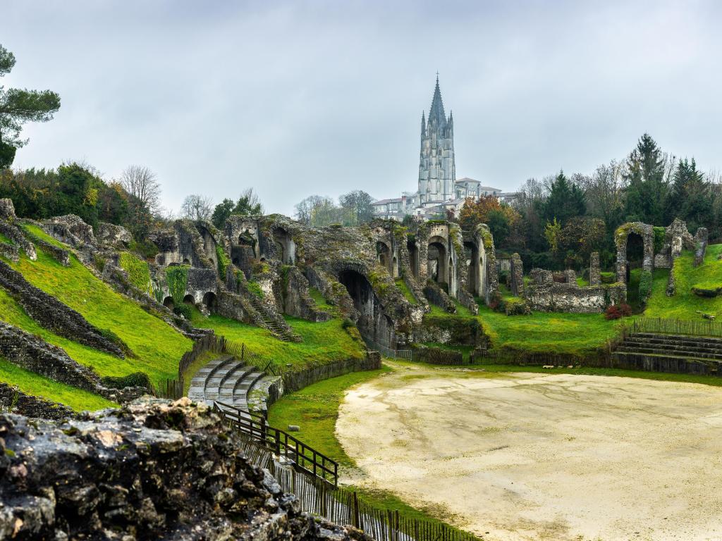 Saintes, Charente Maritime, France. The Ruins Gallo-Roman Amphitheatre of Mediolanum Santonum. Saint Eutrope church listed as World Heritage by UNESCO the arenas in the background.