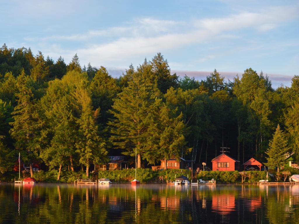 Colored cabins reflected in the water at morning sunshine along the coastline of Saranac Lake in upstate New York 