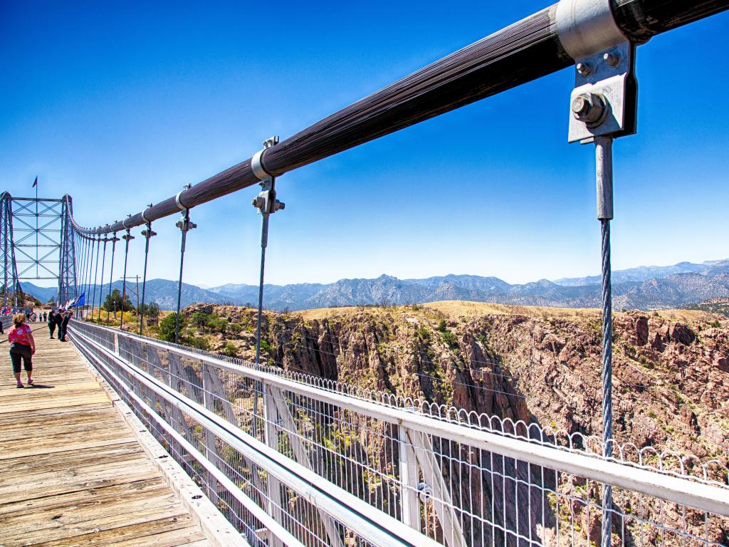Image of the Royal Gorge Bridge from a pedestrian's viewpoint, showing the wooden walkway with a blue sky above